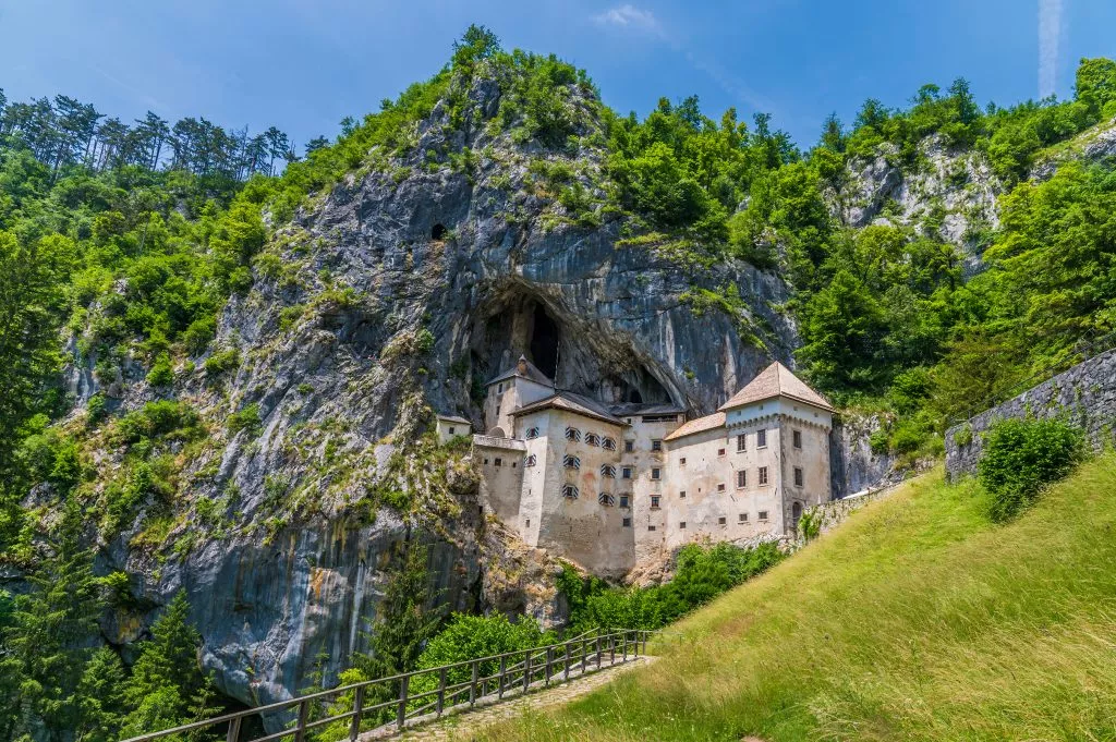 Blick auf die in die Felswand gebaute mittelalterliche Burg in Predjama, Slowenien, im Sommer